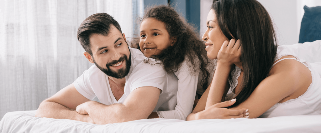 family smiling on bed